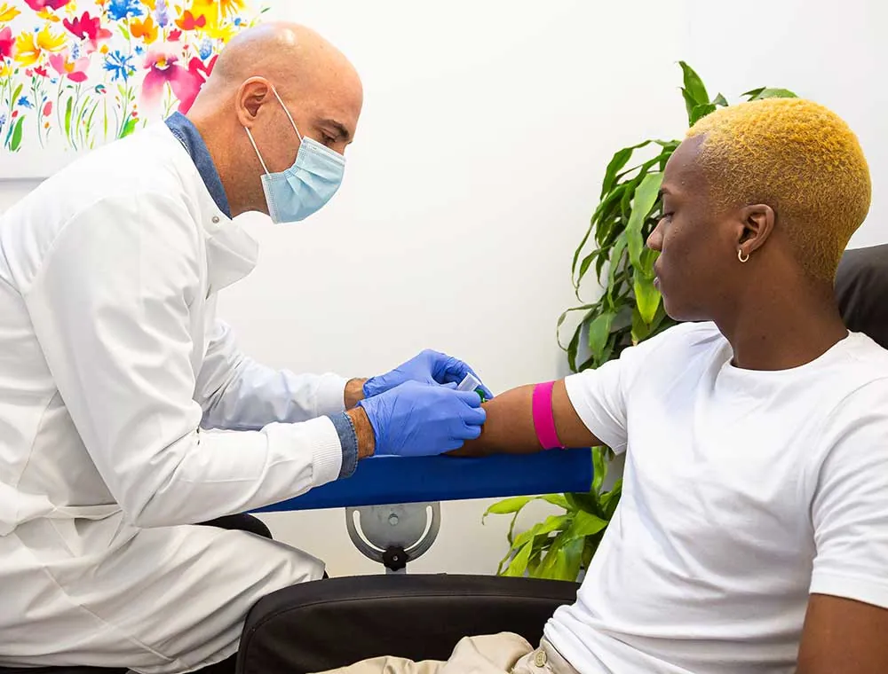 A clinician drawing a blood sample from a person's arm